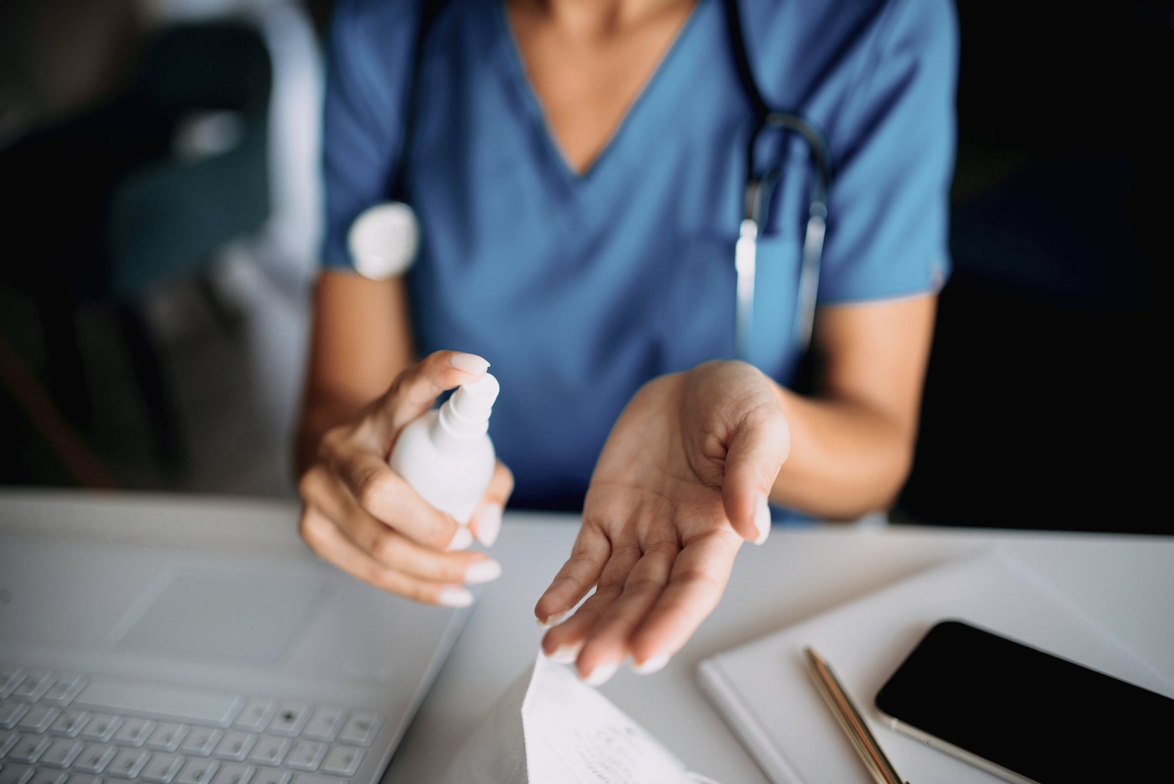 Profesional con ambo azul higienizándose las manos antes de la consulta